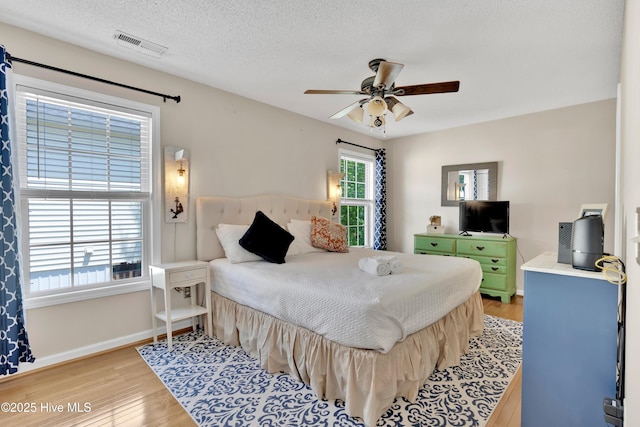 222 NE 36th St, Oak Island, NC 28465 - bedroom featuring light wood-type flooring, ceiling fan, baseboards, visible vents, and a textured ceiling