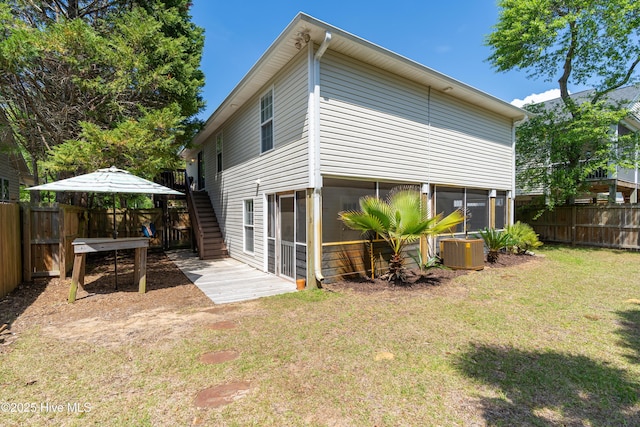 222 NE 36th St, Oak Island, NC 28465 - rear view of property with a sunroom, central AC unit, a yard, a fenced backyard, and stairs