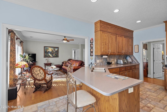 kitchen with a sink, brown cabinets, stone tile floors, and ornamental molding