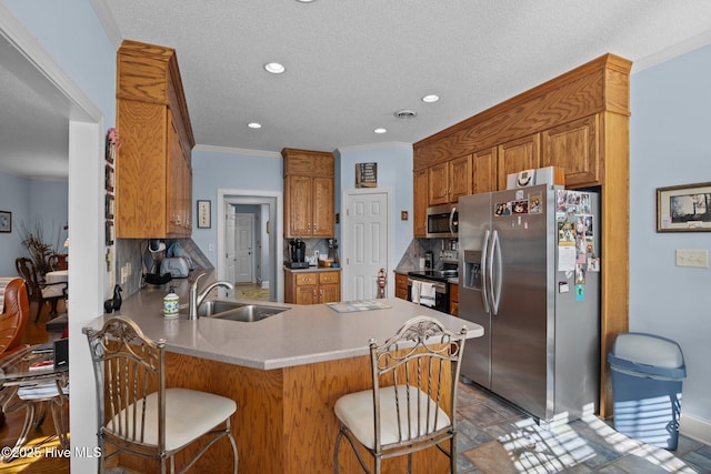 kitchen featuring tasteful backsplash, ornamental molding, a peninsula, stainless steel appliances, and a sink