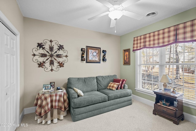 carpeted living area with visible vents, baseboards, and a ceiling fan