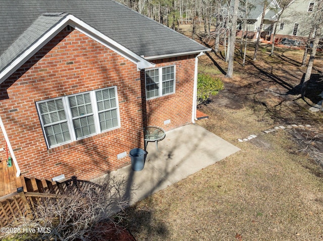 view of side of property with brick siding, crawl space, and roof with shingles