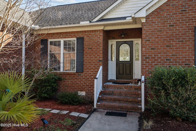 property entrance featuring crawl space, brick siding, and a shingled roof