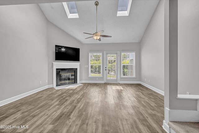 6211 Wrightsville Ave Unit 111, Wilmington, NC 28403 - unfurnished living room with a skylight, wood finished floors, high vaulted ceiling, a ceiling fan, and a premium fireplace