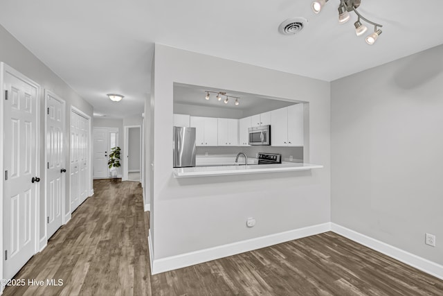 6211 Wrightsville Ave Unit 111, Wilmington, NC 28403 - kitchen featuring appliances with stainless steel finishes, dark wood-style floors, rail lighting, white cabinetry, and light countertops