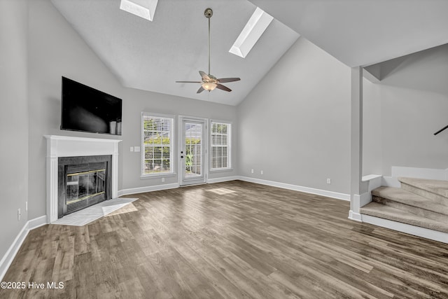6211 Wrightsville Ave Unit 111, Wilmington, NC 28403 - unfurnished living room with a skylight, stairway, wood finished floors, a premium fireplace, and high vaulted ceiling