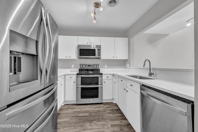 6211 Wrightsville Ave Unit 111, Wilmington, NC 28403 - kitchen featuring stainless steel appliances, white cabinetry, wood finished floors, light countertops, and rail lighting