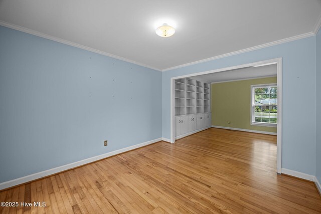spare room featuring baseboards, ornamental molding, and wood finished floors