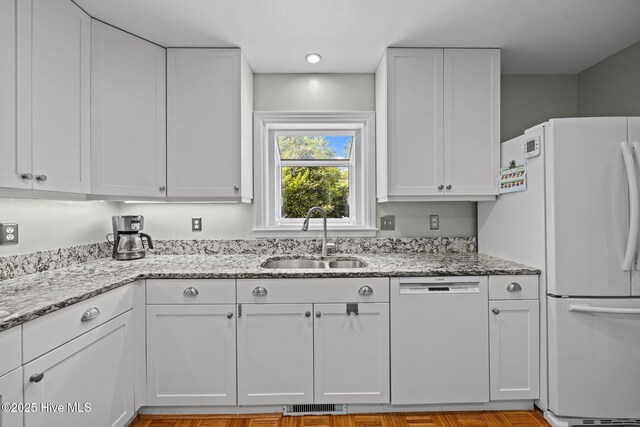 kitchen with a sink, white cabinets, dishwashing machine, and visible vents