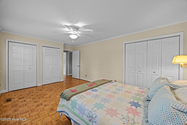 bedroom featuring visible vents, ornamental molding, multiple closets, and baseboards