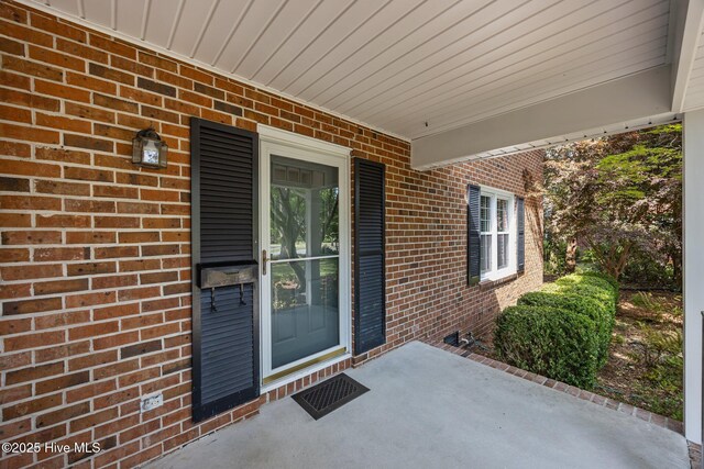 property entrance featuring a porch and brick siding