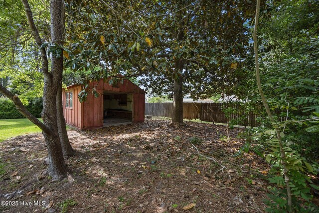 view of yard with fence, an outdoor structure, a storage shed, and a garage