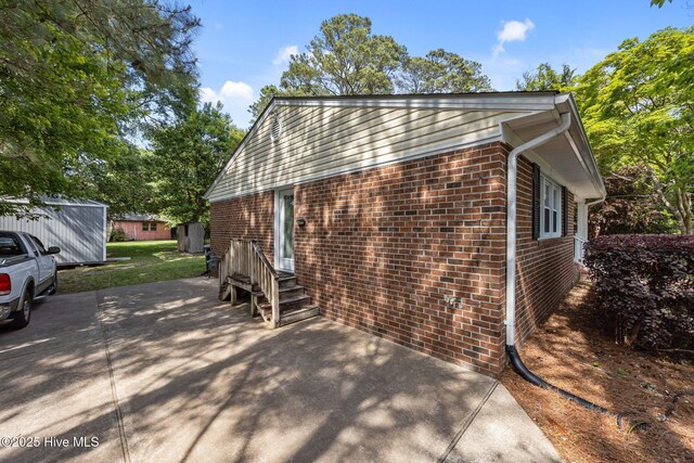 view of side of property featuring brick siding and a patio area