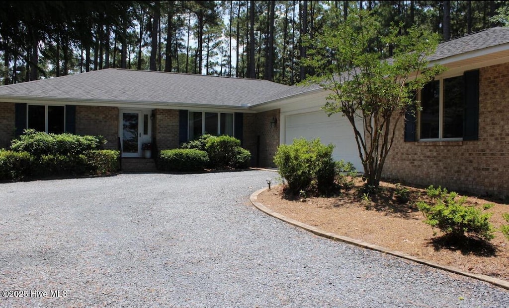 ranch-style house with brick siding, a garage, and driveway