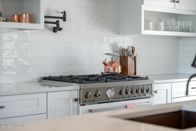 7522 Dunbar Rd, Wilmington, NC 28411 - kitchen featuring tasteful backsplash, white cabinets, light countertops, open shelves, and stainless steel range oven