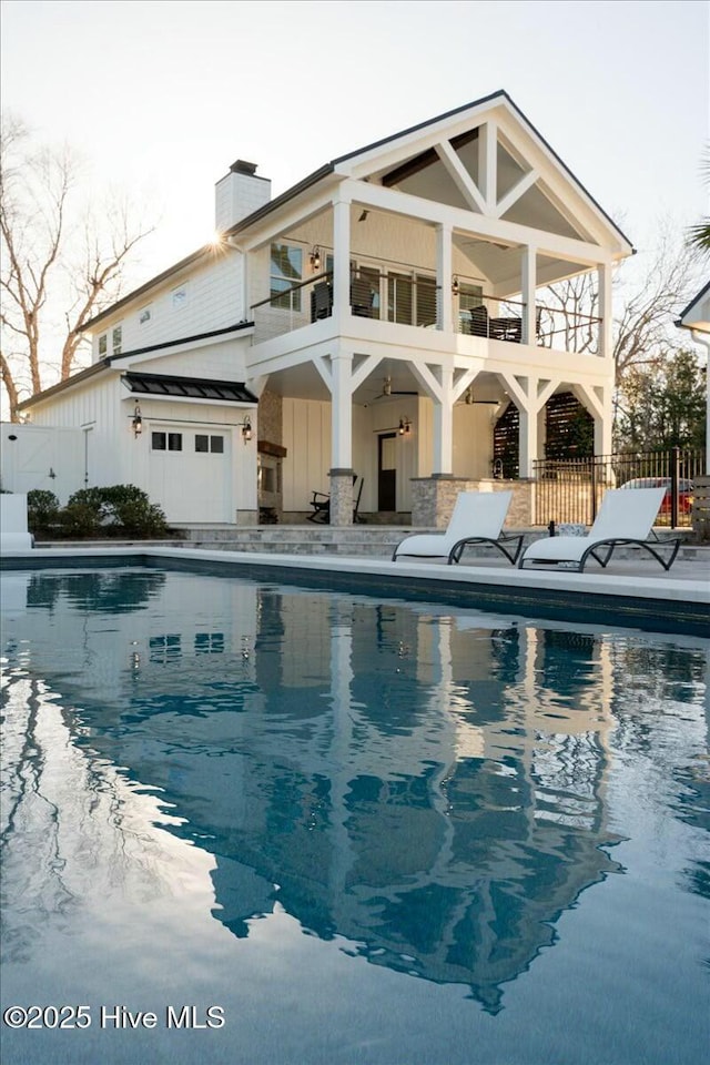 7522 Dunbar Rd, Wilmington, NC 28411 - rear view of property with board and batten siding, a balcony, an outdoor pool, and a patio area