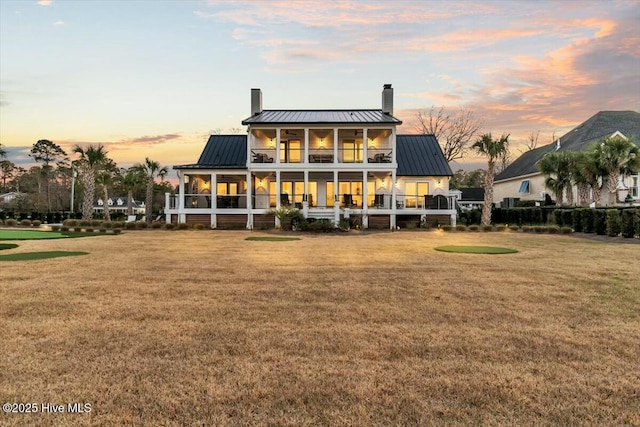 7522 Dunbar Rd, Wilmington, NC 28411 - rear view of property with a chimney, a standing seam roof, a balcony, and a lawn