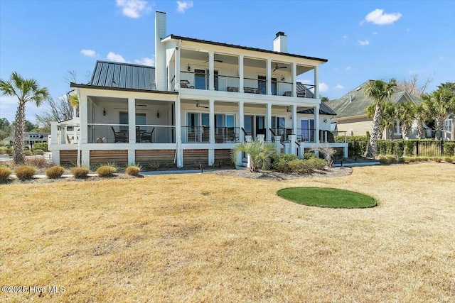 7522 Dunbar Rd, Wilmington, NC 28411 - back of property featuring a balcony, a chimney, a yard, and a metal roof