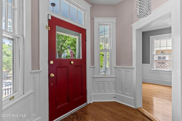 entryway featuring a healthy amount of sunlight, a wainscoted wall, and dark wood finished floors