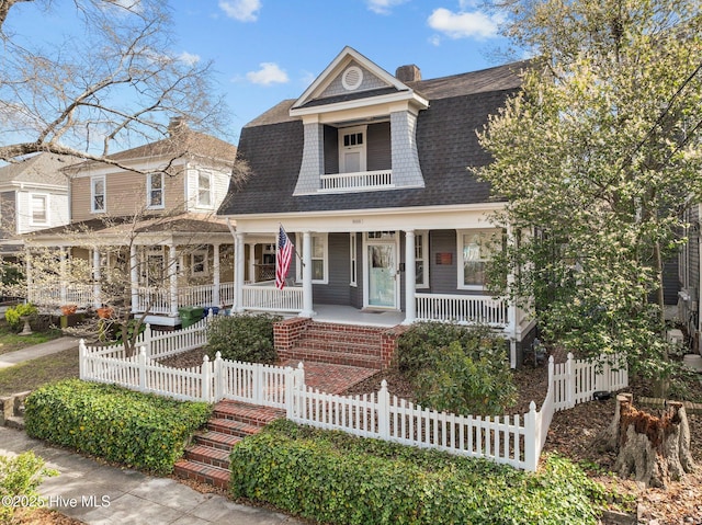 shingle-style home featuring a porch, a shingled roof, and fence private yard