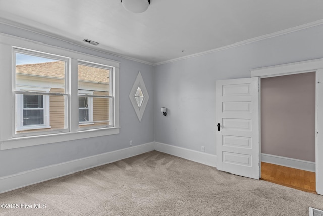carpeted spare room with visible vents, baseboards, and crown molding