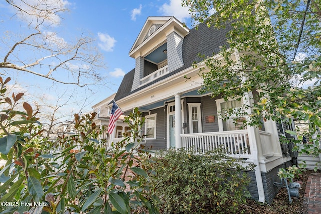 view of front of house with a shingled roof, a balcony, and covered porch