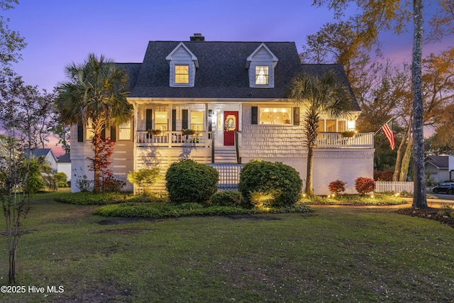 3001 E Yacht Dr, Oak Island, NC 28465 - new england style home with a chimney, covered porch, and a front lawn