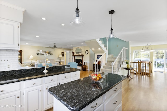 3001 E Yacht Dr, Oak Island, NC 28465 - kitchen featuring white cabinets, a ceiling fan, a peninsula, a fireplace, and decorative backsplash