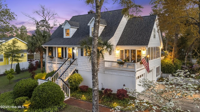 3001 E Yacht Dr, Oak Island, NC 28465 - cape cod-style house with covered porch, fence, stairs, a chimney, and a shingled roof