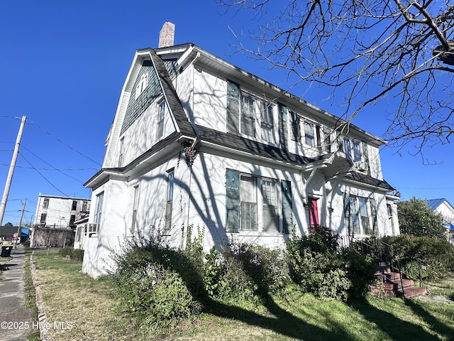view of side of property featuring a chimney and a lawn