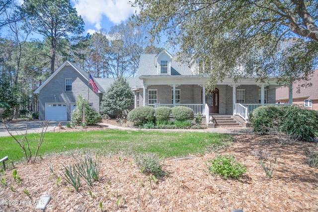 new england style home with driveway, covered porch, a garage, and brick siding