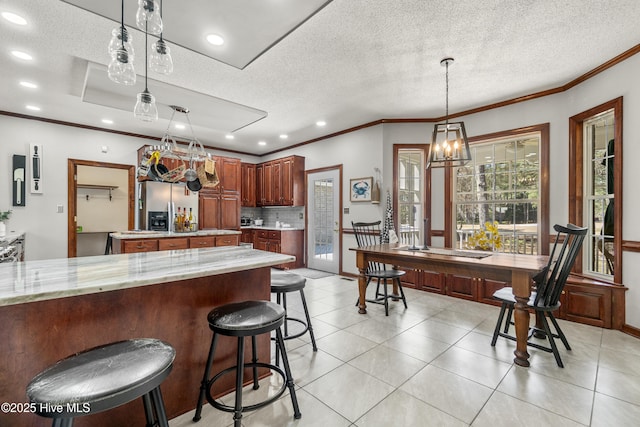 kitchen with decorative light fixtures, tasteful backsplash, ornamental molding, and stainless steel fridge