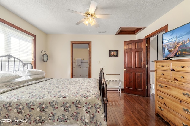bedroom featuring dark wood-style flooring, a textured ceiling, visible vents, and ceiling fan