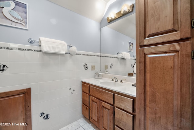 bathroom with tile walls, tile patterned flooring, vanity, and wainscoting
