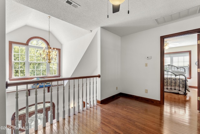 corridor featuring visible vents, a healthy amount of sunlight, and hardwood / wood-style flooring