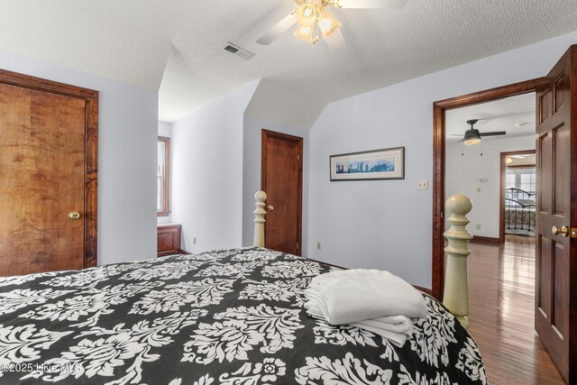 bedroom featuring a closet, a ceiling fan, wood finished floors, a textured ceiling, and visible vents
