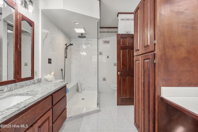 bathroom featuring tile walls, a shower stall, toilet, tile patterned floors, and vanity