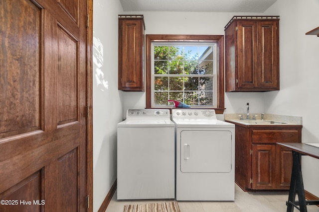laundry room with a sink, cabinet space, baseboards, and separate washer and dryer