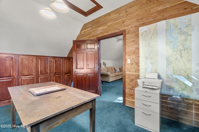 office space with ceiling fan, wood walls, vaulted ceiling, and dark colored carpet