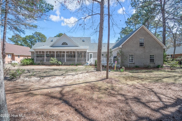 back of property featuring a sunroom and brick siding