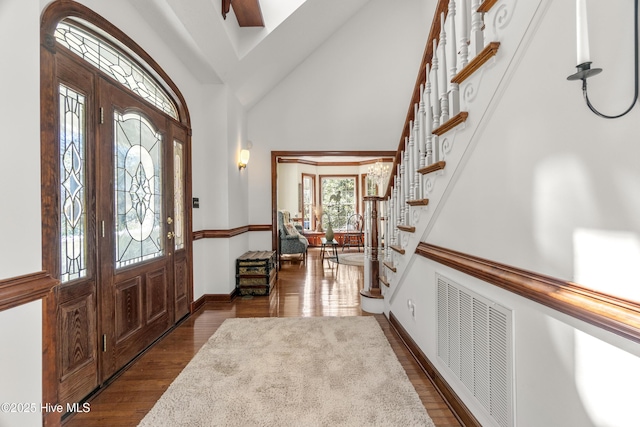 foyer entrance featuring high vaulted ceiling, visible vents, baseboards, stairs, and dark wood-type flooring