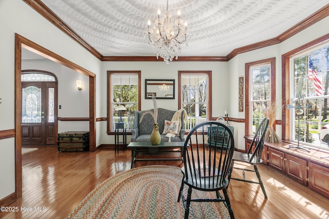 dining room with baseboards, ornamental molding, a chandelier, and light wood-type flooring
