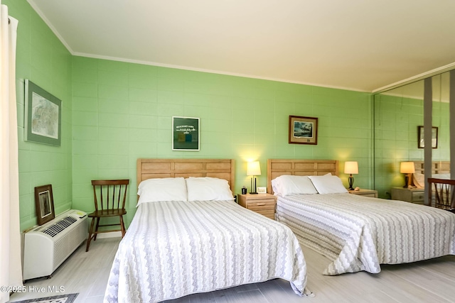 bedroom with tile walls, wood finished floors, ornamental molding, and an AC wall unit