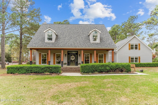 new england style home featuring a front yard, a porch, and a shingled roof
