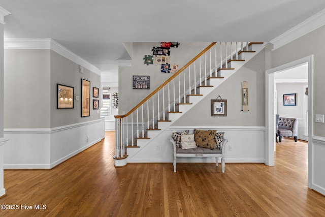 stairway featuring baseboards, ornamental molding, and wood finished floors