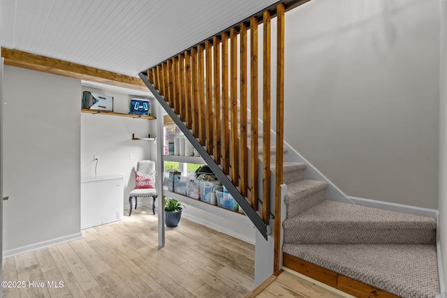 staircase with baseboards, beam ceiling, and wood finished floors