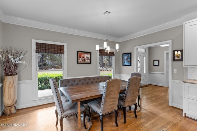 dining room featuring a chandelier, a wealth of natural light, light wood finished floors, and a wainscoted wall