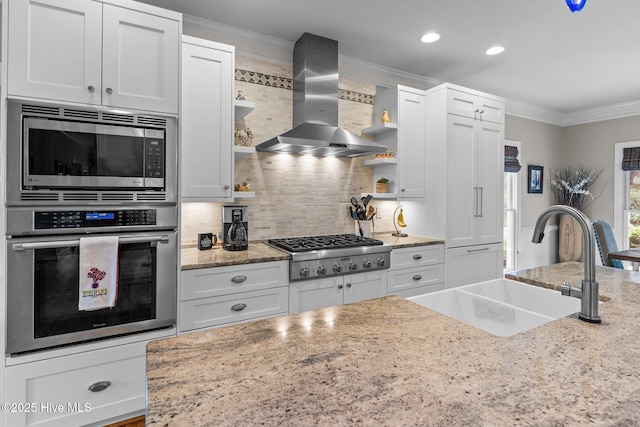 kitchen featuring crown molding, open shelves, wall chimney exhaust hood, stainless steel appliances, and a sink