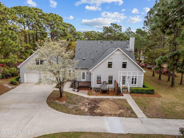 view of front of property featuring a garage, roof with shingles, a front lawn, a chimney, and driveway