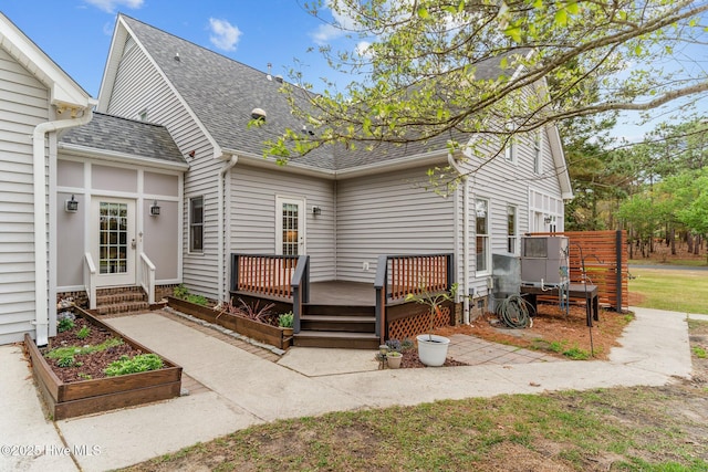 rear view of property featuring a wooden deck and a shingled roof